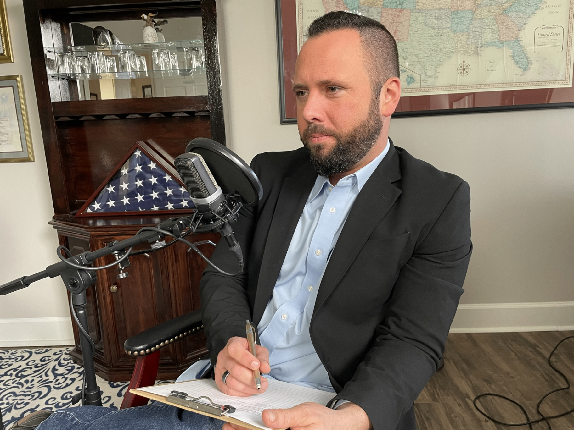 Austin Arthur taking notes behind a studio microphone while recording an After Thought interview in Winter Garden, Florida